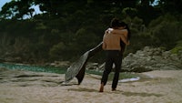 a man and woman hugging on the beach