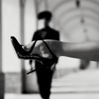 a black and white photo of a woman holding a high heeled shoe