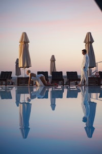 a man and woman standing in the pool at dusk