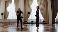 a man and woman standing in a room with chandeliers