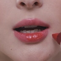 a woman is putting lipstick on her lips