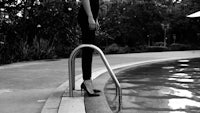 black and white photo of a woman standing next to a pool