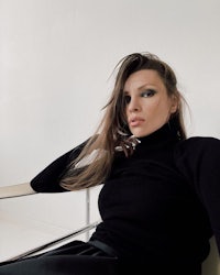 a woman in a black turtleneck sitting on a chair