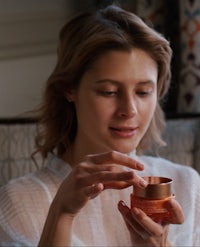 a woman holding a jar of cream