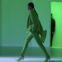 a woman in a green suit walking down a runway