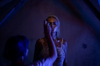 a woman is standing in a dark room with a blue light behind her