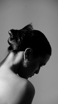 a black and white photo of a woman with ear piercings