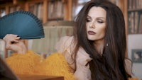 a woman with long hair holding a fan