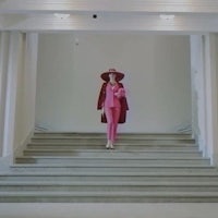 a woman in a pink coat standing on stairs