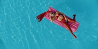 a woman laying on a pink inflatable float in a pool