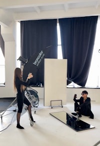 a woman and a man standing in front of a camera in a studio